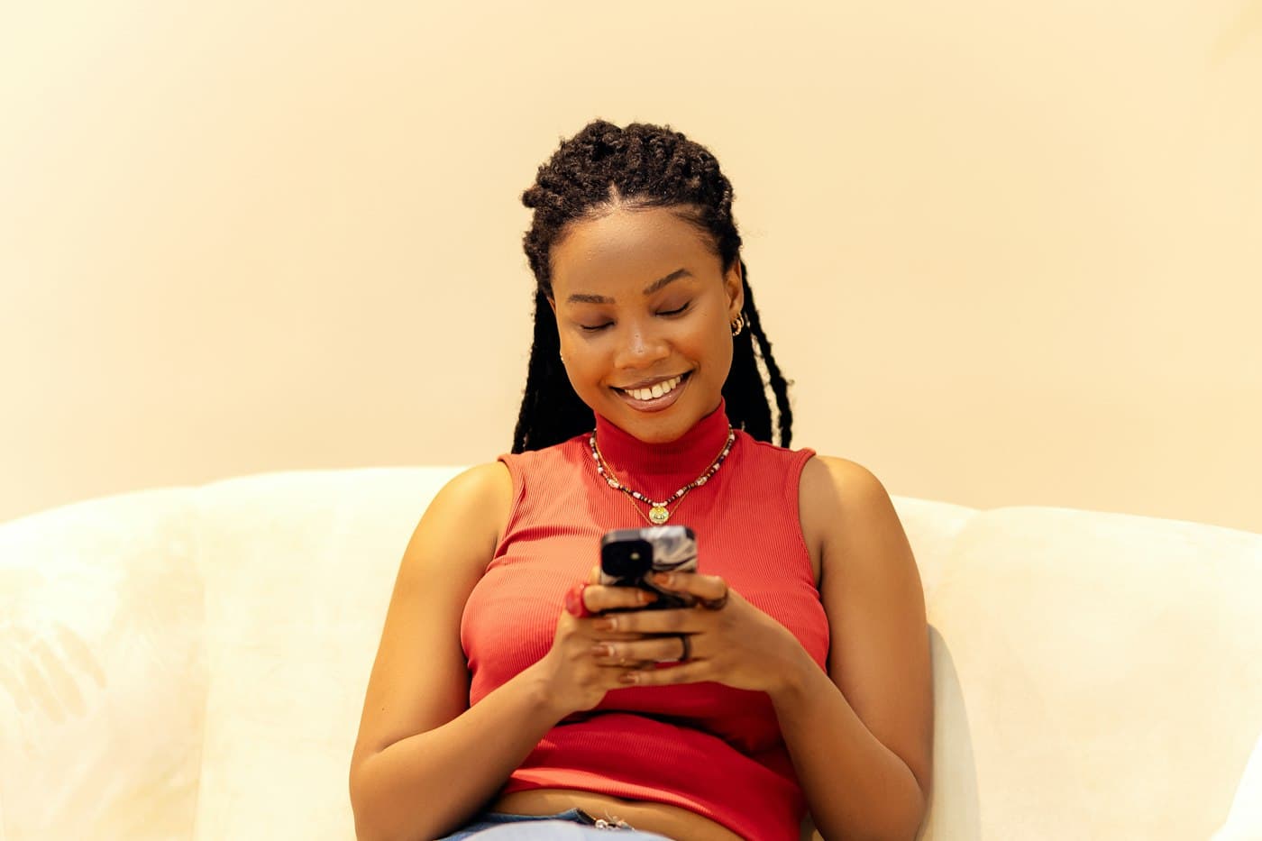 A smiling woman on a sofa, reading her phone